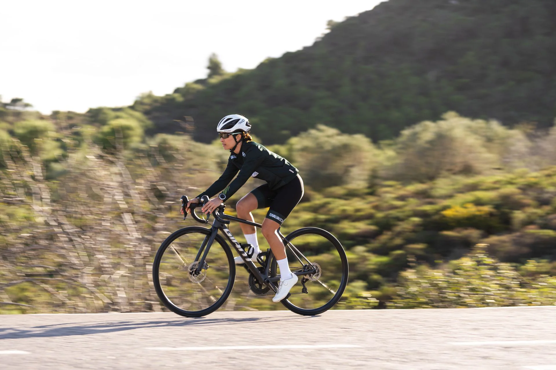 Female professional cyclist riding a road bike through the Spanish mountains